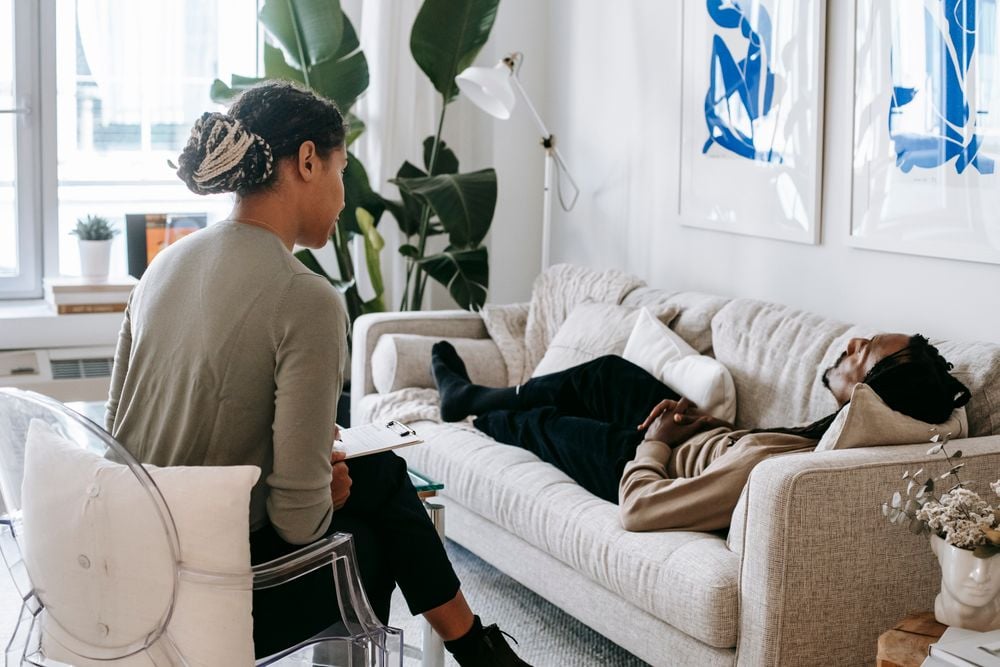 Therapist leaning forward to listen as a client talks through a difficult decision on a couch